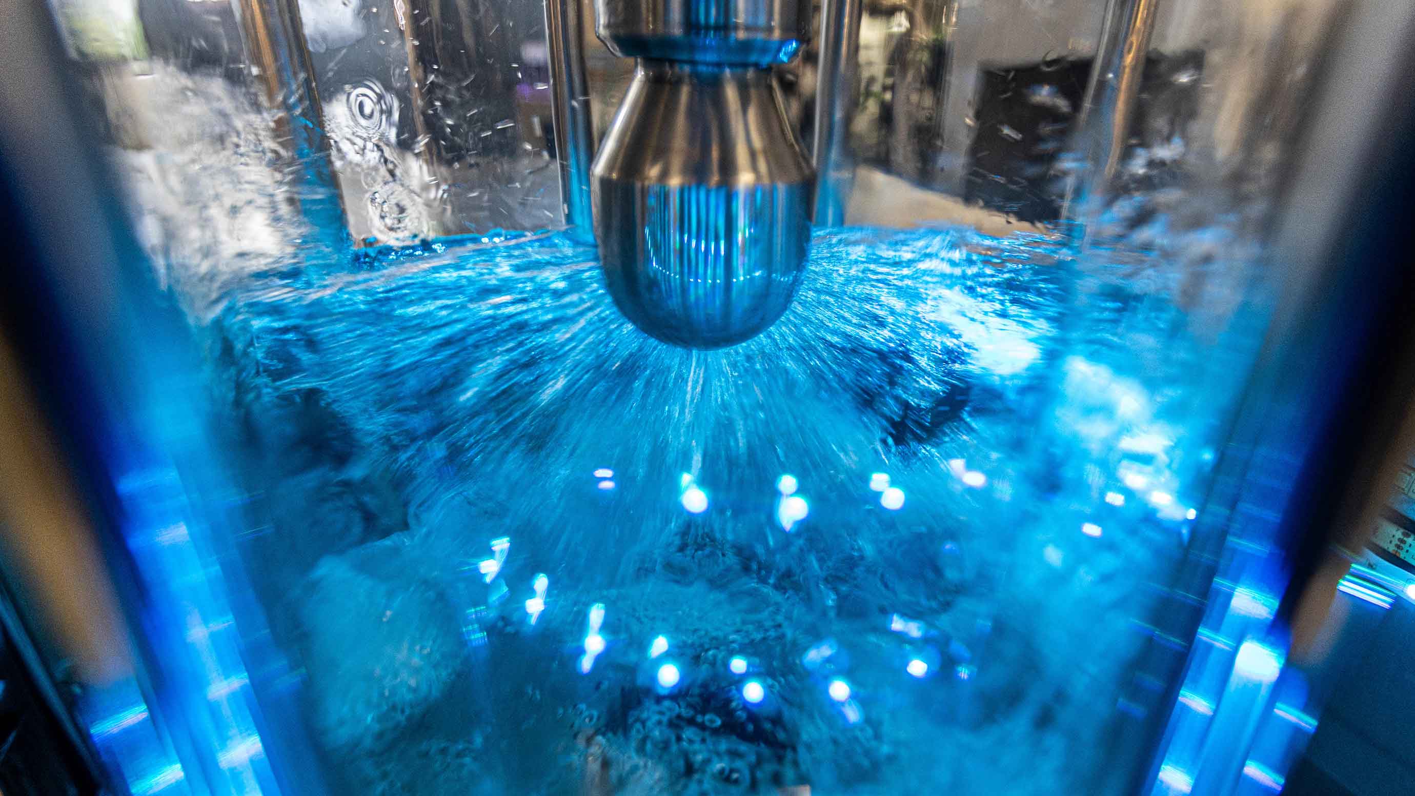 Nahaufnahme eines Wasserstrahls in einer transparenten Kammer mit blauer Beleuchtung